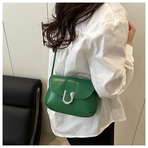 Detail of green minimalist faux leather shoulder bag with bold silver U-shaped metal buckle