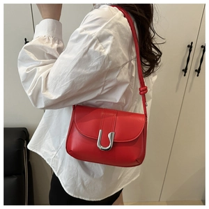 Detail of red leather shoulder bag featuring a silver U-shaped clasp and knotted strap
