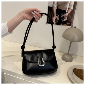 Detail of minimalist black PU leather shoulder bag with silver U-shaped buckle and knotted strap