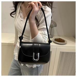 Close-up of black leather crossbody bag with silver U-shaped metal buckle and knot detail