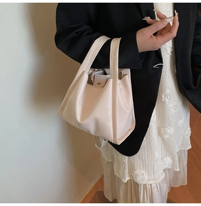 Detailed view of beige lychee textured leather bucket bag carried by a model