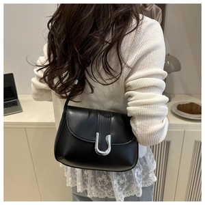Close-up of black leather shoulder bag featuring a silver metal U-shaped buckle closure