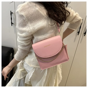 Detailansicht der rosa Klappentasche mit Goldkette und Schultergurt an einem Damenmodel
