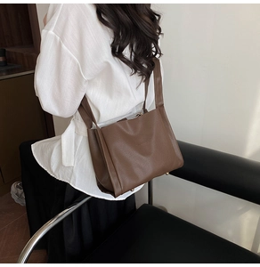 Close-up of dark brown lychee texture leather bag with protective gold metal base studs