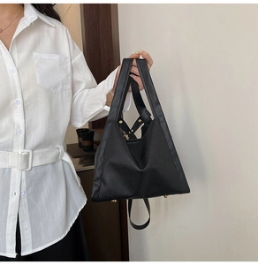 Detail of black lychee-grain leather handbag with unique polygonal shape and gold studs