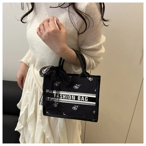 Close-up of black jacquard tote bag featuring white rose pattern and lace bow detail