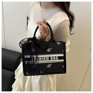 Detail of black floral tote bag with white rose prints and lace bow decoration