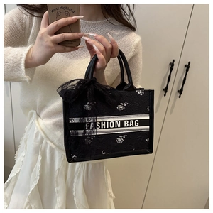 Detail of black jacquard tote bag featuring floral embroidery and lace ribbon bow