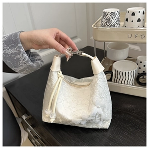 Detalle del bolso de encaje beige con flores en 3D y elegantes hebillas metálicas