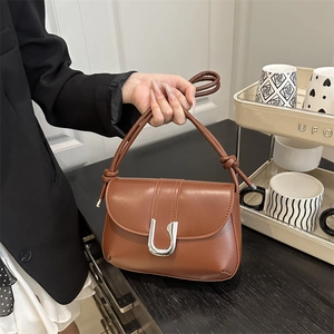 Brown leather shoulder bag with a large silver horseshoe buckle and knotted handle design