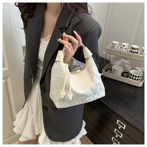 Detalle del bolso de encaje blanco con asa de cuero y adorno de cordón ajustable