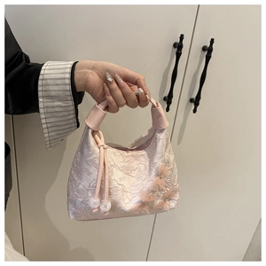 Detalle de bolso rosa plisado con apliques de mariposas 3D y borlas de perlas finas