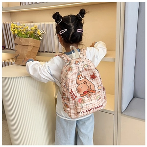 Zaino per bambini a scacchi rosa con stampe capibara su sfondo di scaffale in legno
