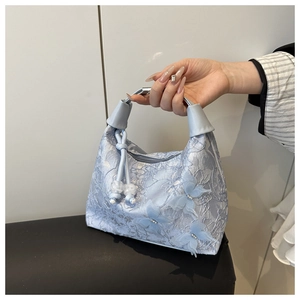 Detalle de bolso de encaje azul claro con aplicaciones de mariposas 3D y perlas