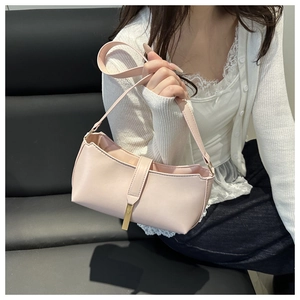 Detail of light pink PU leather shoulder bag with gold metal clasp and hanging pendant