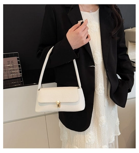 Detail view of the white woven texture and golden clasp on this stylish shoulder bag