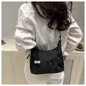 Detail der bestickten Schmetterlinge und Blumenmuster auf schwarzer Tasche mit Perlen