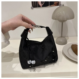 Detalle de bolso negro con grabados florales y adornos de mariposas en relieve 3D