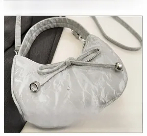 Détail du sac à main plissé argenté avec nœud et logo métallique JINGPIN