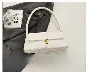 Detail of white textured shoulder bag with gold metal buckle on a minimalist background