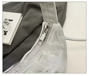 Détail de la fermeture éclair en métal sur un sac à main argenté à texture plissée chic