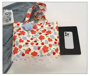 Close-up of floral canvas tote bag featuring a blue star plush charm and vibrant prints