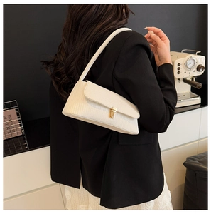 Detail of white pleated shoulder bag with a vintage gold square clasp on a textured surface