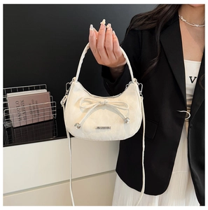 Détail du sac croissant blanc avec un nœud élégant et le logo métallique JINGPIN