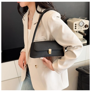 Detail of black baguette bag showing intricate woven texture and gold metal buckle