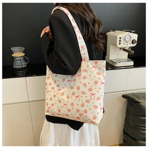 Model back view of a large floral canvas tote bag with pink rose and red bow patterns