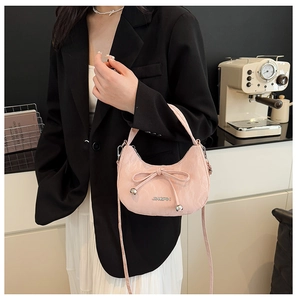 Vue détaillée d'un sac demi-lune rose avec nœud et pendentif sphérique argenté