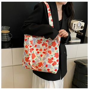 Floral canvas tote bag worn on shoulder, featuring red and purple flower patterns