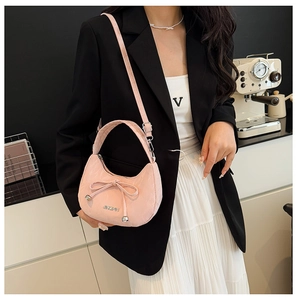 Détail du sac demi-lune rose avec nœud et perles argentées sur un mannequin