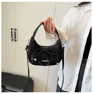 Vue détaillée du sac croissant noir texturé avec nœud et logo argenté