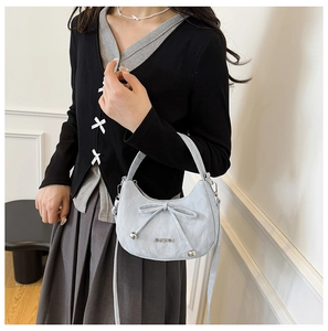 Détail du sac croissant bleu clair avec finition texturée et nœud papillon chic
