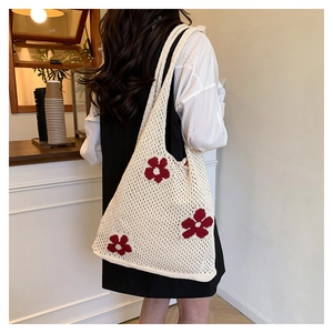 Detail of cream crochet tote bag featuring red floral embroidery and mesh weave texture