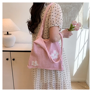 Vue détaillée du sac cabas au crochet rose avec motifs floraux sur l'épaule du modèle