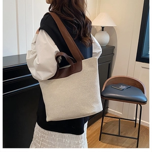 Canvas tote bag with brown leather straps shown in a cozy interior setting