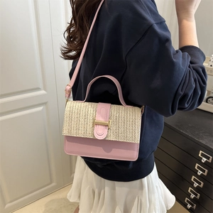 Borsa a tracolla intrecciata rosa e beige con fibbia dorata indossata in un ambiente interno