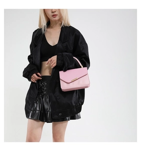 Detail of pink faux leather handbag with lychee texture and gold metal bar accents