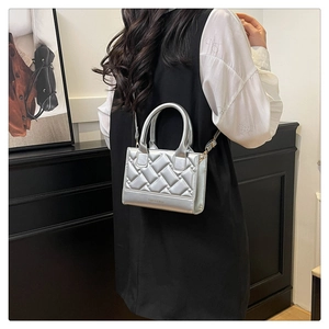 Detail of silver quilted crossbody bag with top handle and metallic leather texture