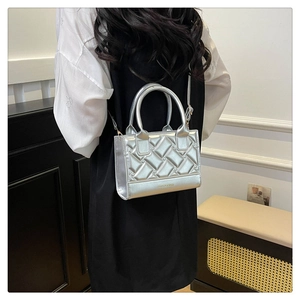 Close-up of silver quilted crossbody bag with top handles and fashion slogan detail