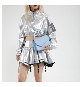 Detail of light blue crossbody bag featuring mixed textures and a gold metallic clasp