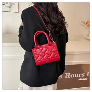 Detail of red quilted square bag with adjustable strap worn with a black blazer