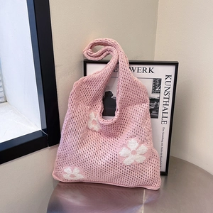 Sac fourre-tout en tricot rose avec motif floral blanc et maille ajourée sur une table