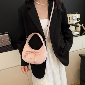 Sac à bandoulière rose en demi-lune avec nœud et sangle réglable dans un décor chic