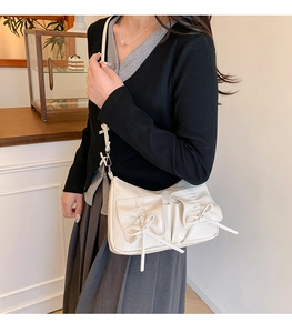 Détail du sac à bandoulière blanc crème avec poches à nœuds et finition cuir brillant