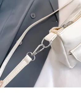 Détail de la boucle en métal argenté et de la bandoulière en cuir PU blanc du sac