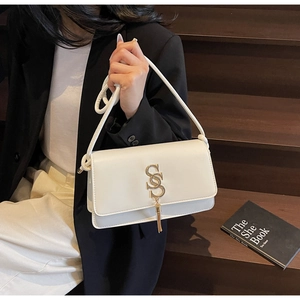 Detail of ivory crossbody bag with golden interlocking S-logo and metal tassel charms