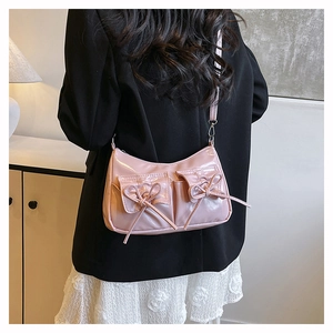 Détail d'un sac bandoulière en cuir verni rose avec nœud et poches avant à rabat